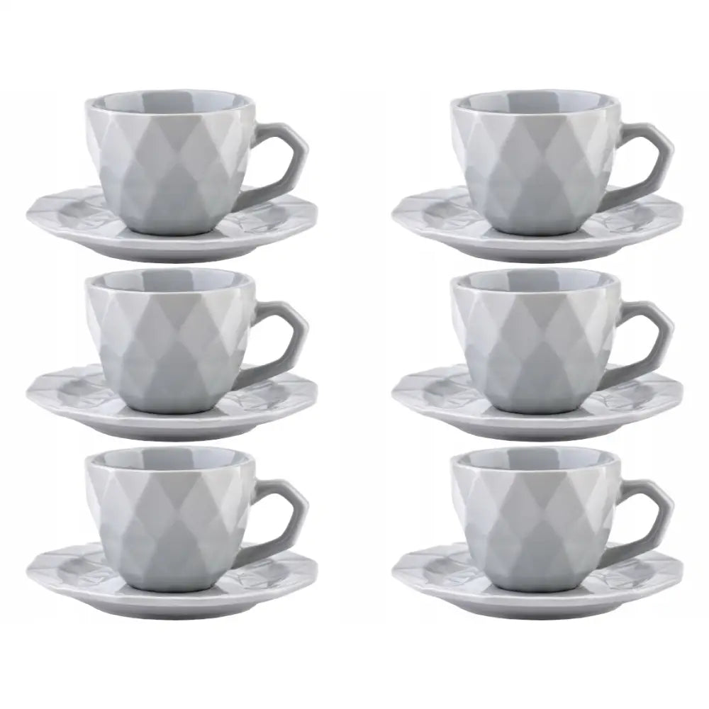 Seks grå kopper med tilhørende fasetterte asjetter, geometrisk design, avbildet fra skrå vinkel.