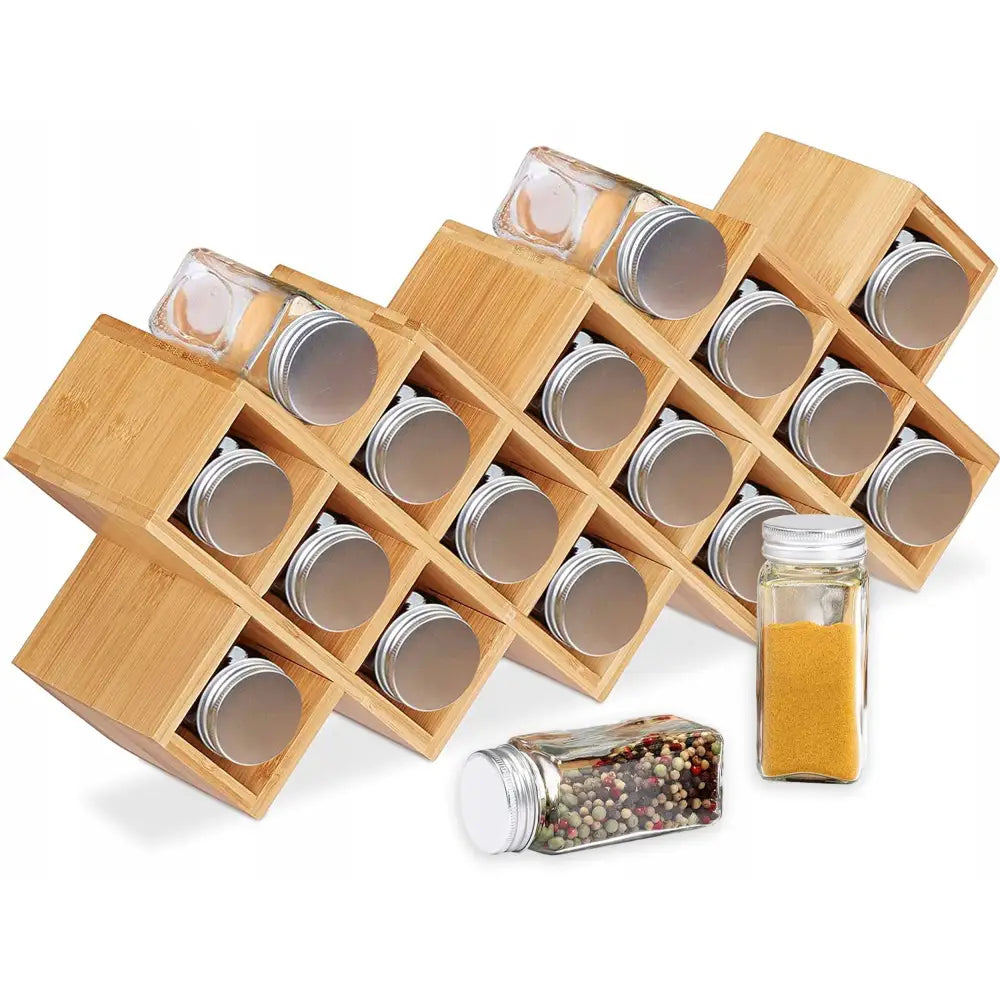 Krydderstativ i lyst bambustre med skrå rom, fylt med glasskrukker og to krydderglass plassert foran.