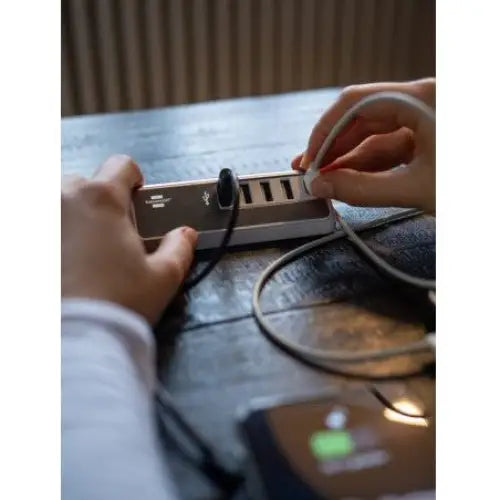 Lader USB estilo stal, sølv ladestasjon med flere USB-porter kobles til på mørkt trebord.