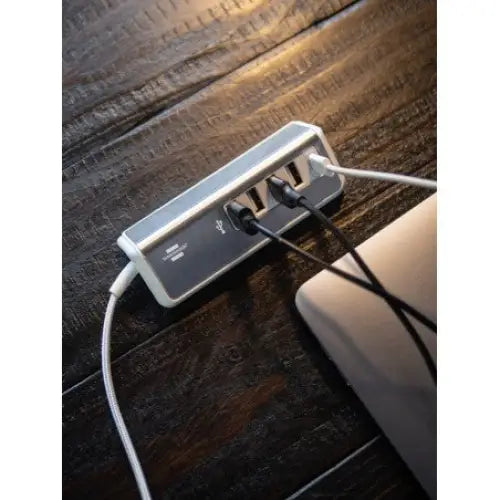 Lader USB estilo stal, rektangulær ladehub med flere USB-porter og tilkoblede ledninger på mørkt trebord.