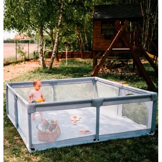Lekegrind for barn med tørrbasseng, sett skrått ovenfra utendørs på gress med barn som leker inni.