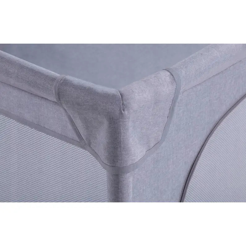 Lekegrind for barn, detalj av mykt polstret hjørne med nettingfelt og solid søm i lyst grått tekstil.