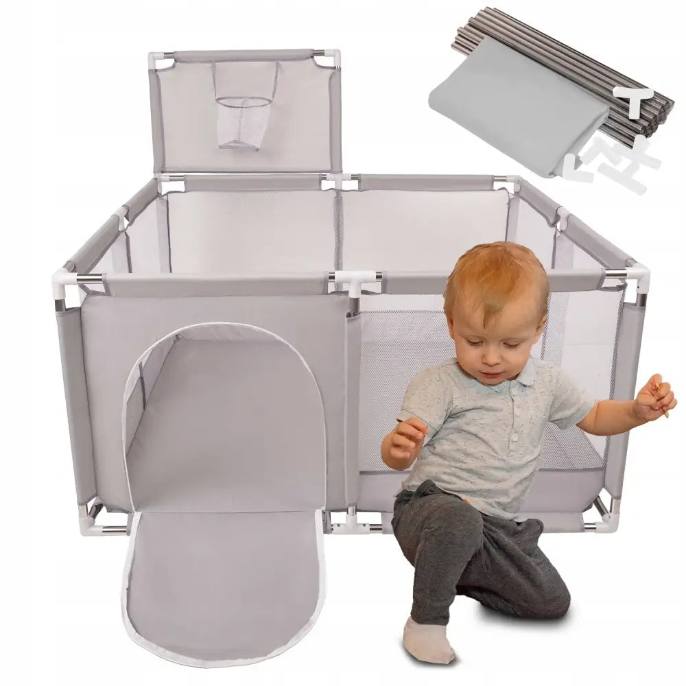 Lekegrind med oppbevaringskurv, grå firkantet modell med netting, åpen inngang og gutt sittende foran.