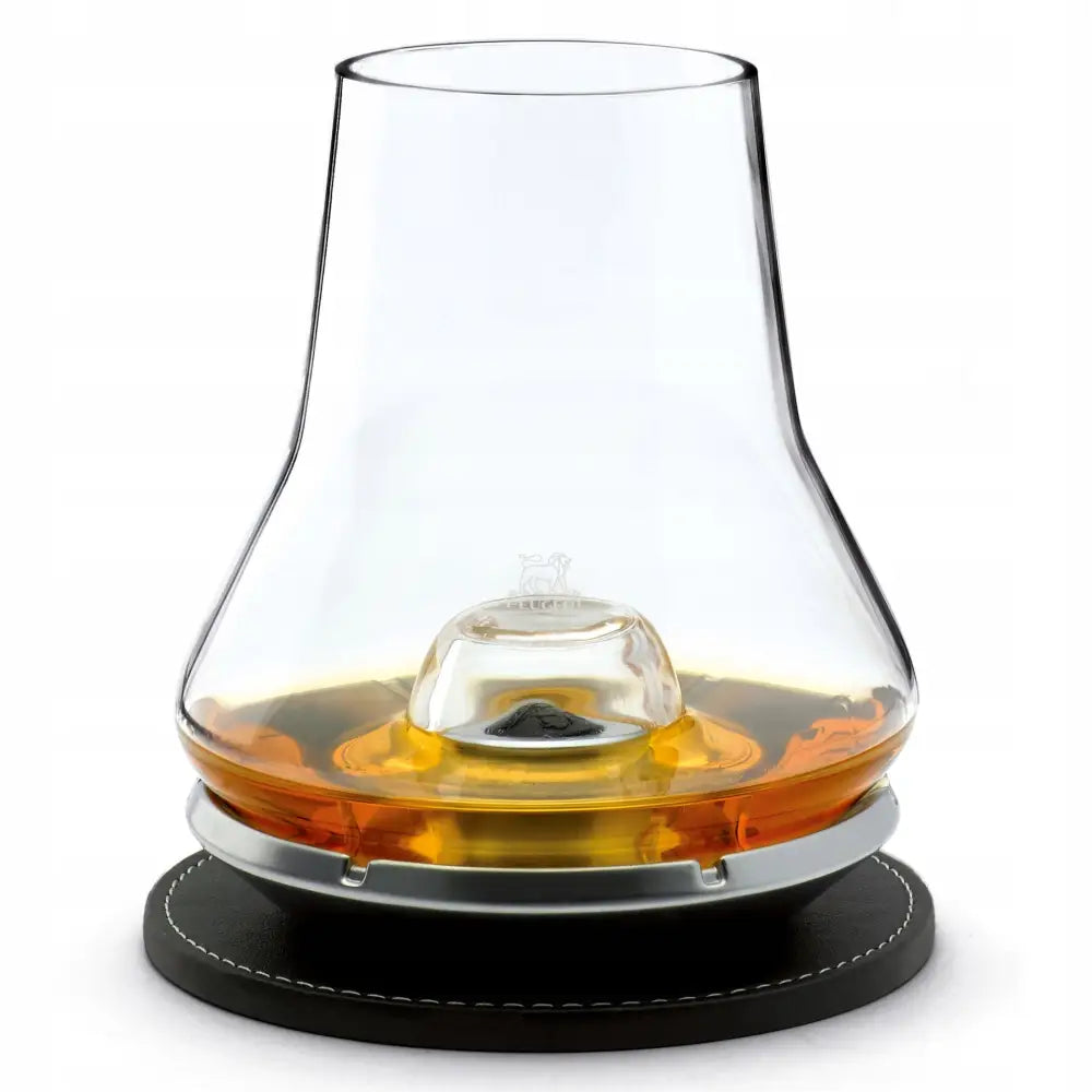 Les Impitoyables whiskyglass med kjølende base på sort skinnbrikke, fylt med gyllen whisky.