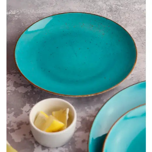 Blå turkis keramikktallerken med brun kant og prikker, sett ovenfra, sitronskål og ekstra tallerken i forgrunnen.
