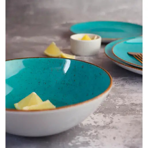 Lubiana Boss dyp keramikkbolle med turkis innside, sitrusbiter i skålen, matchende servisedeler bak.