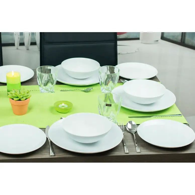 Lubiana Boss hvitt middagsett, fire kuverter med tallerkener, skåler og glass på mørkt bord med telys og blomster.