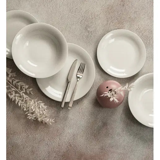Lubiana Eto middagsservise i hvitt porselen, tallerkener og skåler med bestikk, rosa vase og tørkede blader.