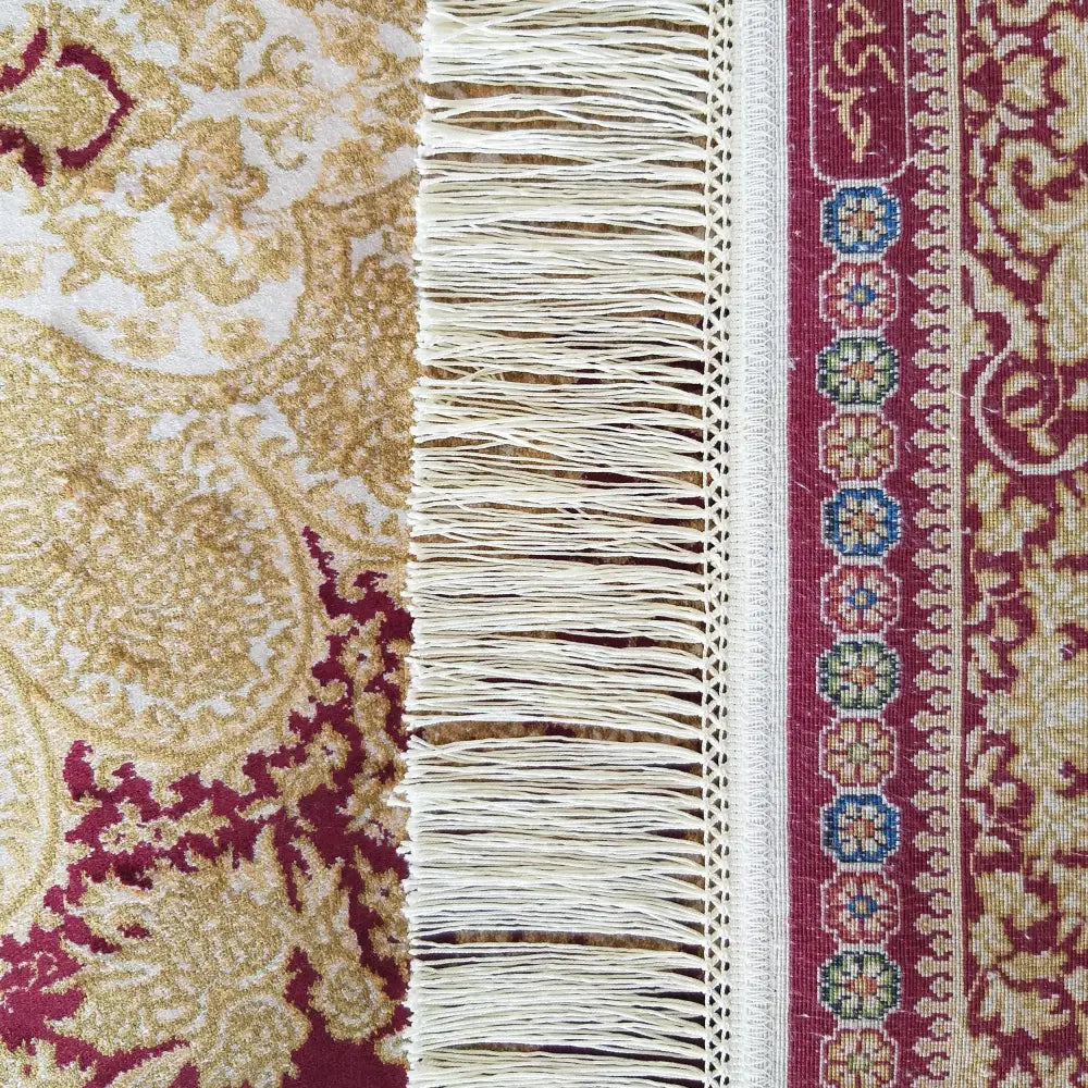 Qum Silk teppe, nærbilde av kanten med røde og gullfargede mønstre, frynser og fargerike blomster.