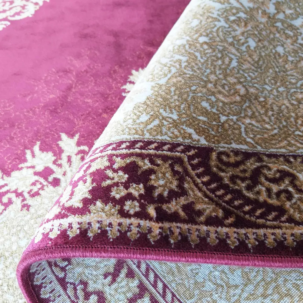 Qum Silk 02 rød teppe, nærbilde av oppbrettet kant som viser vinrøde mønstre og tykk silkestruktur.