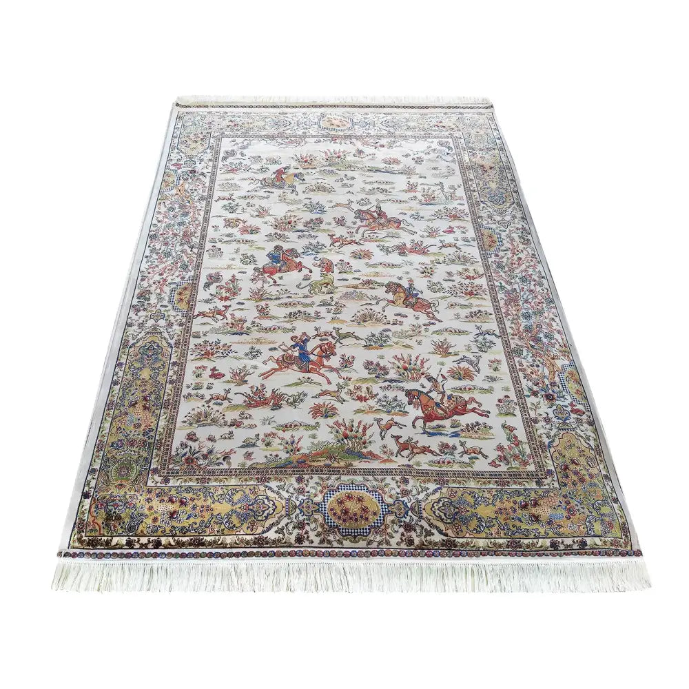 Qum Silk kremet teppe 160x230 cm, sett skrått ovenfra med fargerike jaktmotiver, blomster og dekorativ kant.