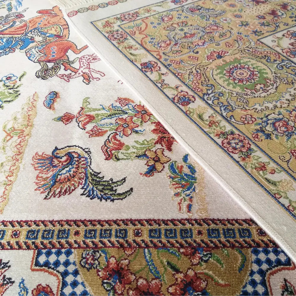 Qum Silk kremet teppe 160x230 cm, nærbilde av intrikate blomstermønstre i blått, rødt, grønt og gull.