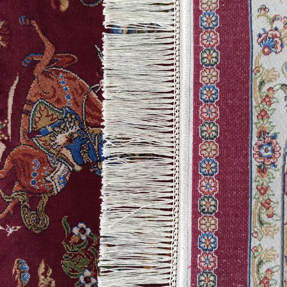 Qum Silk Tepe, detaljbilde av rød kant med hvite frynser, mønstret bord og fargerike blomster.