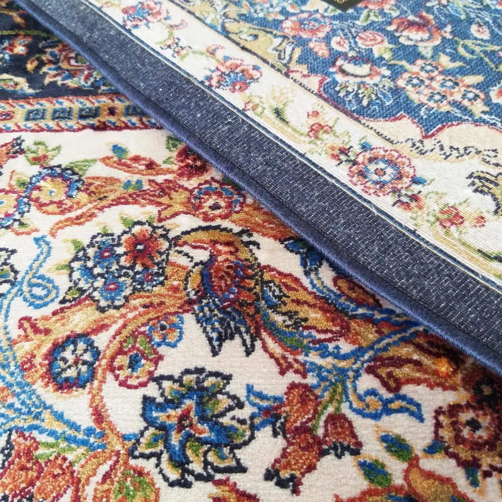 Qum Silk Tepe i marineblått, nærbilde som fremhever det orientalske blomstermønsteret og teksturen i kanten.