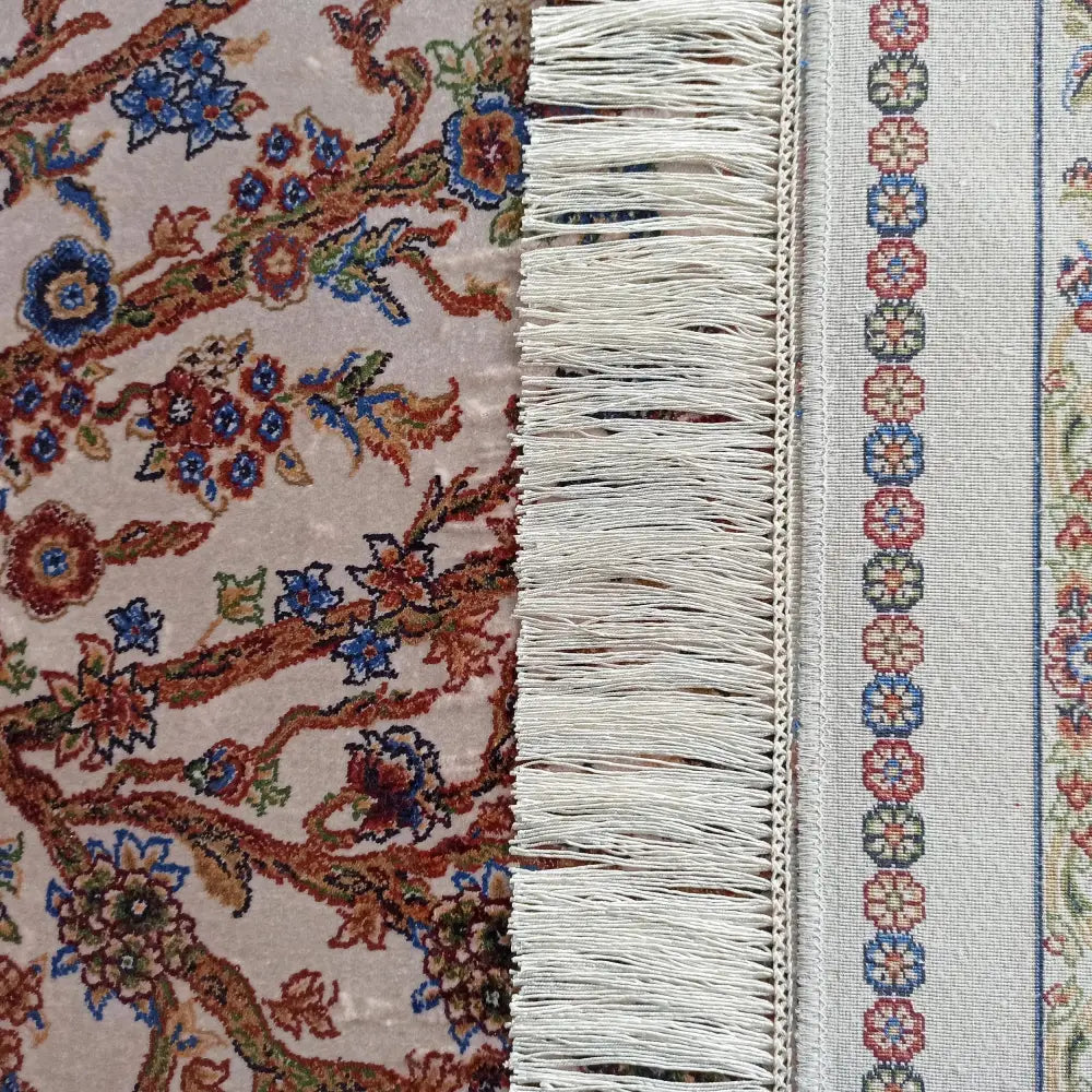 Qum Silk Tepe 200x300 cm, nærbilde av fargerikt blomstermønster og kremfargede frynser langs kanten.