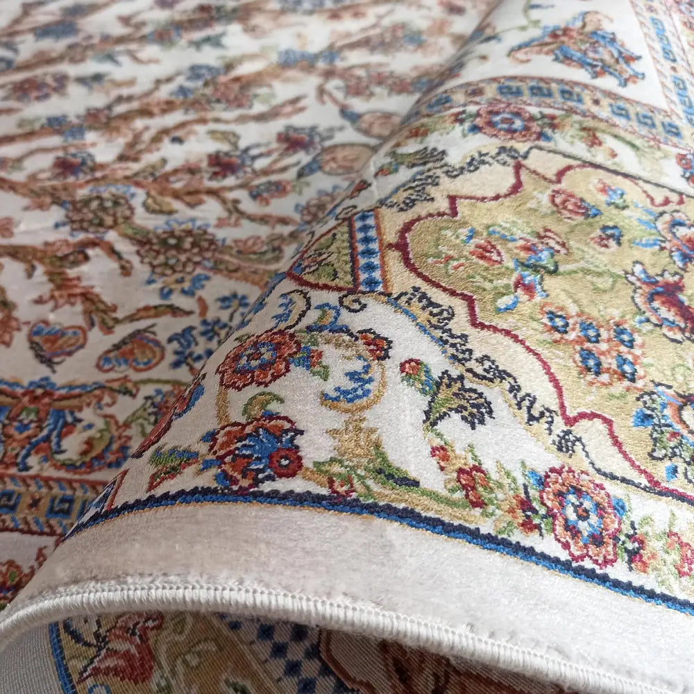 Qum Silk Tepe i krem, nærbilde av kanten med detaljerte orientalske mønstre i blått, rødt og grønt.