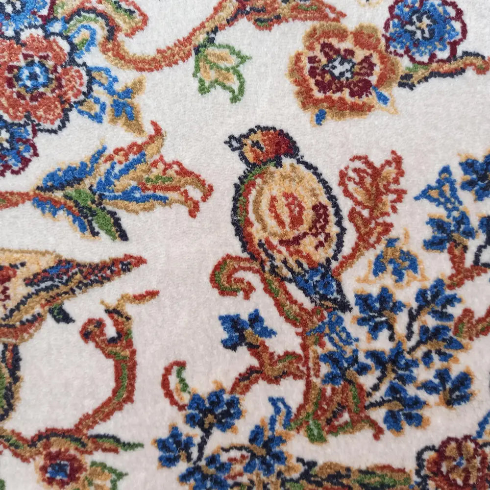 Qum Silk Tepe teppe, nærbilde av fuglemotiv og fargerike blomster på kremfarget, detaljert tekstil.