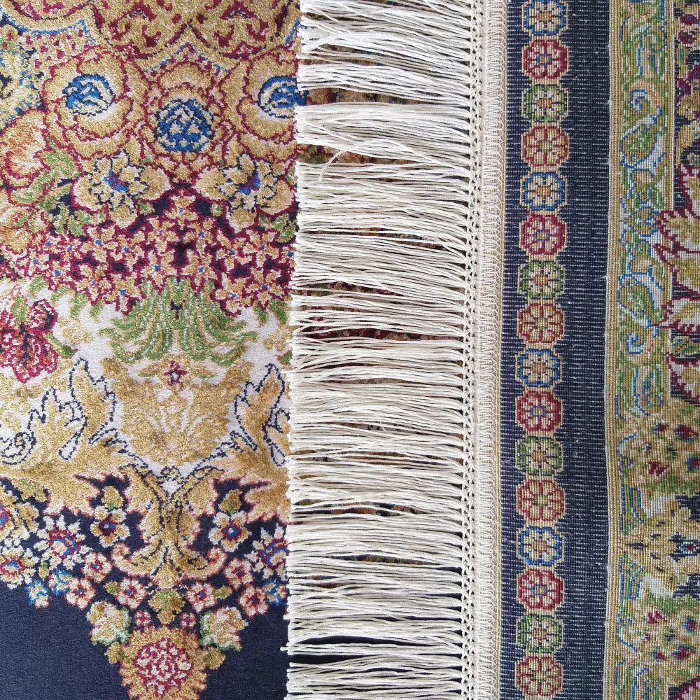 Qum Silk Tepe Navy teppe, nærbilde av blå og gulldetaljer i det intrikate orientalske mønsteret med frynser.