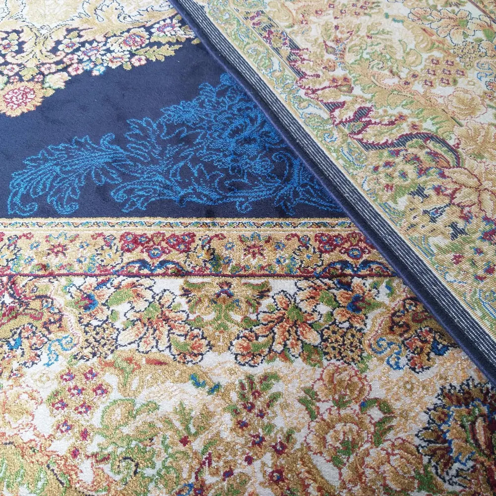 Qum Silk Tepe Navy teppe, nærbilde av blått og beige blomstermønster med gull og tydelig tekstur.