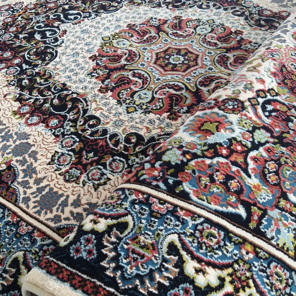 Orientalsk teppe i kremfarge, detalj av mønster i svart, rødt og blått, delvis rullet opp.