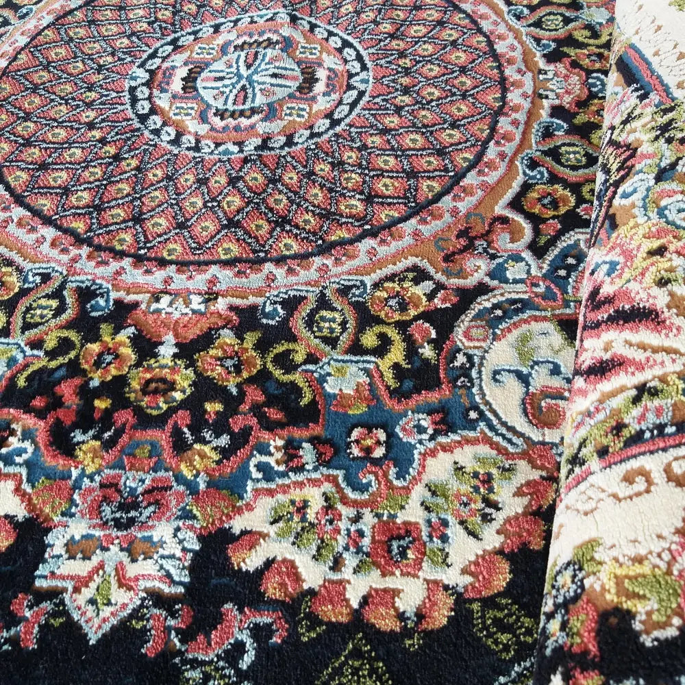 Iransk Tepe, nærbilde av sirkulær midtdel med detaljerte røde, blå og gule ornamenter og synlig garnstruktur.