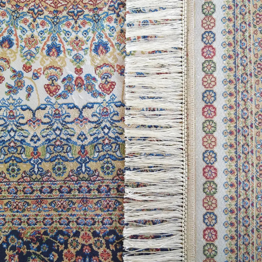 Qum Silk Tepe, nærbilde av kremfarget teppe med blå, beige og røde ornamenter samt fargerik kant.