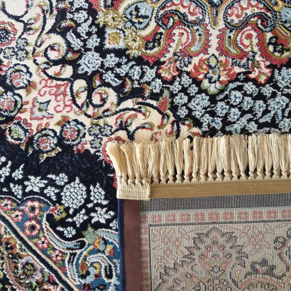 Luksus Iran-teppe med orientalske mønstre i blått, rødt og beige, detalj av frynser og synlig bakside.