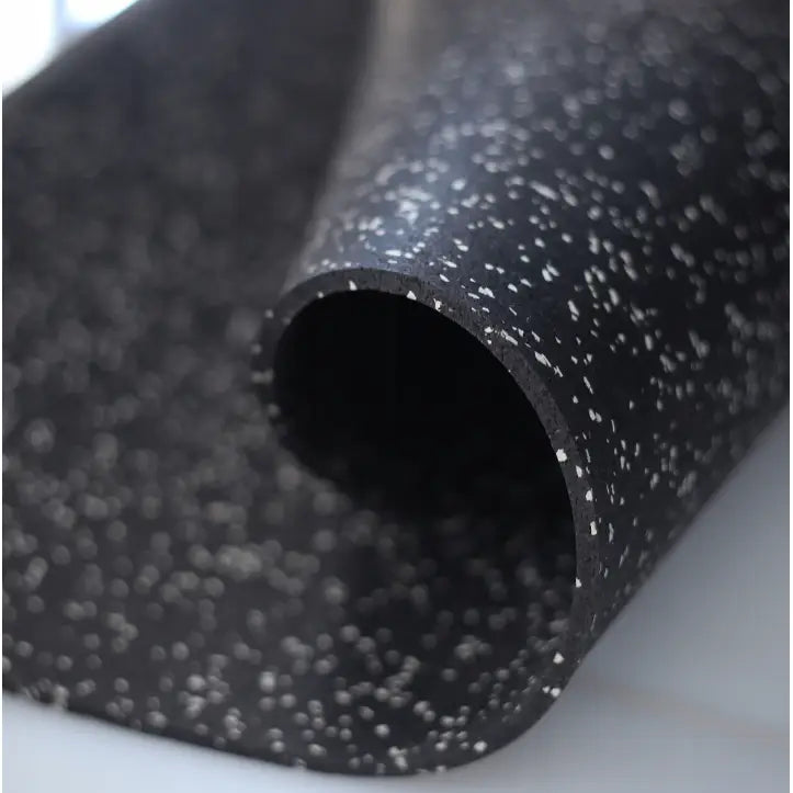 Lyddempende matte for tredemølle, nærbilde av sort overflate med hvite prikker rullet sammen, viser tekstur.