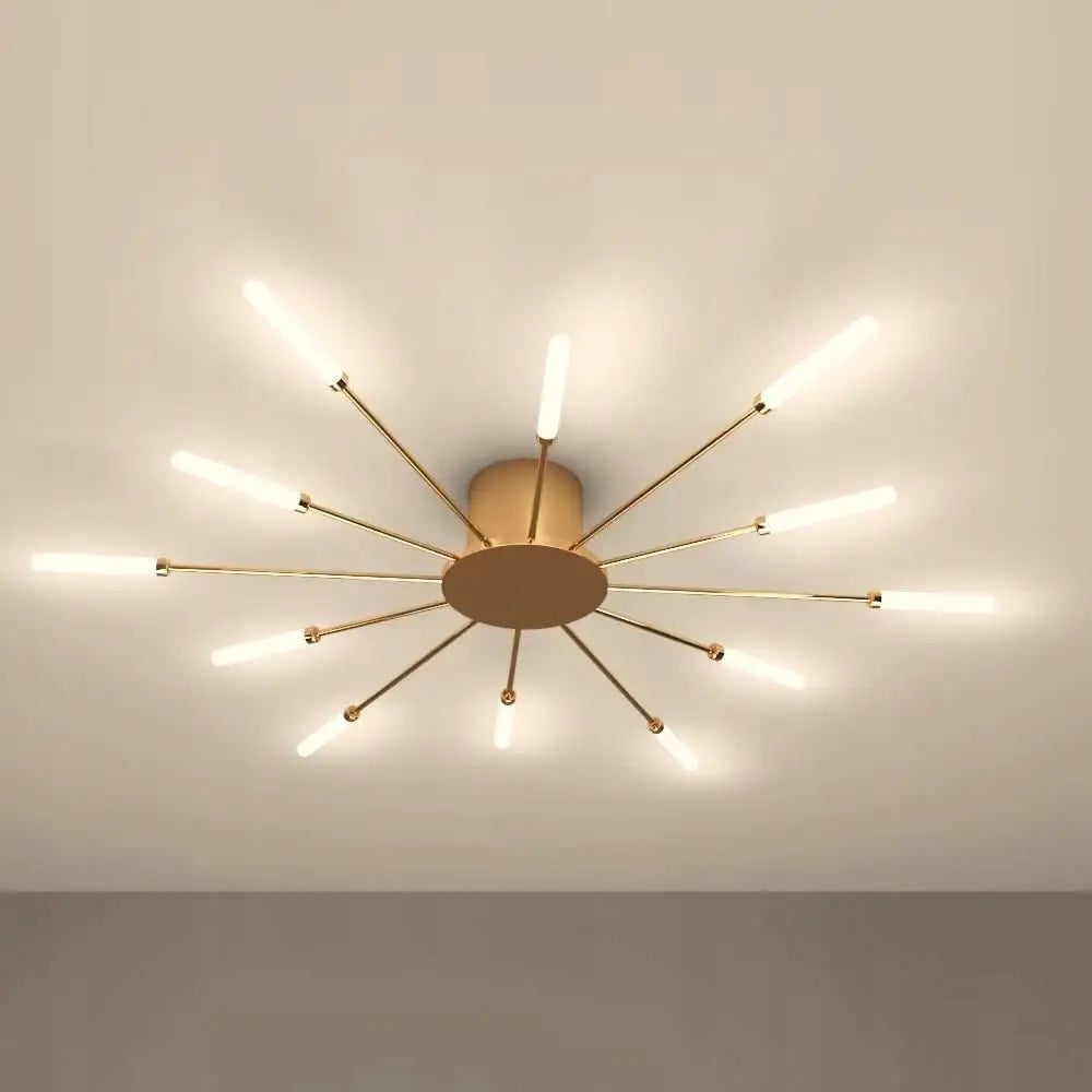 Lysekrone LED i messing, sett fra undersiden med tolv armer og lysstaver mot lyst tak.