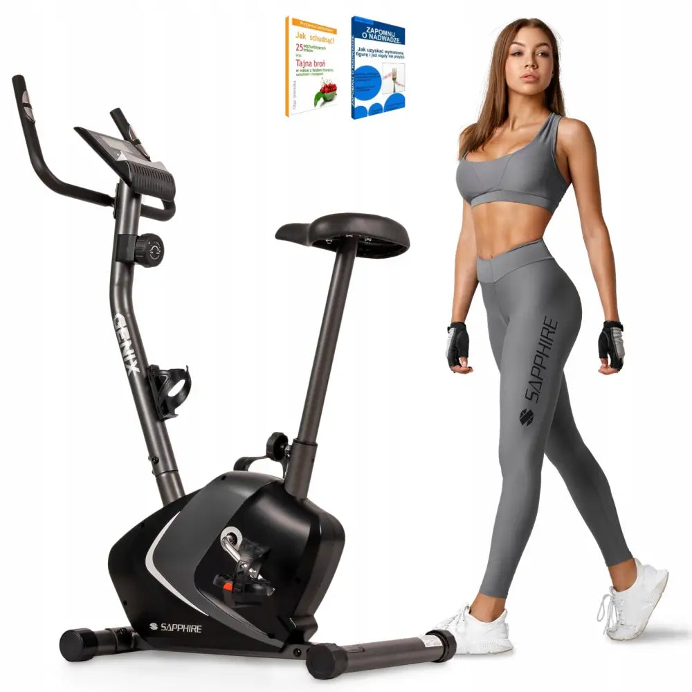 Ergometersykkel Sapphire Genix, sidevisning med justerbart sete og display, kvinne i grått treningstøy ved siden av.