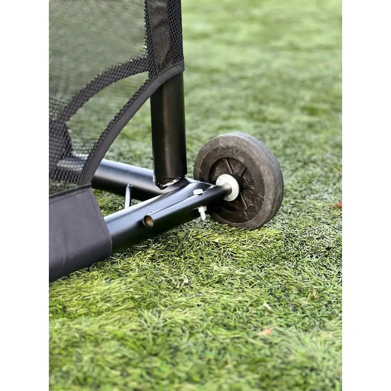 Fotballmål GIZA 5x2m, sort ramme med netting og hjul, nærbilde av hjulfeste på kunstgress.