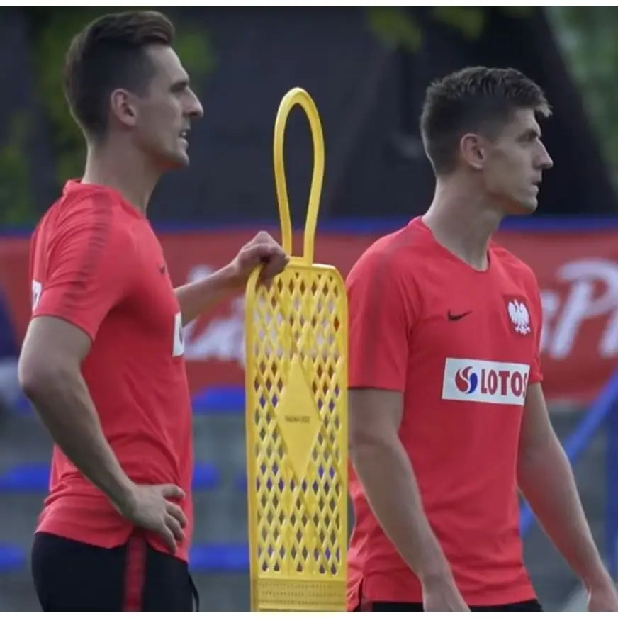 Målmuren ELITE 180 cm gul, profilbilde med to menn i rødt og gul plastmannequin for fotballtrening utendørs.