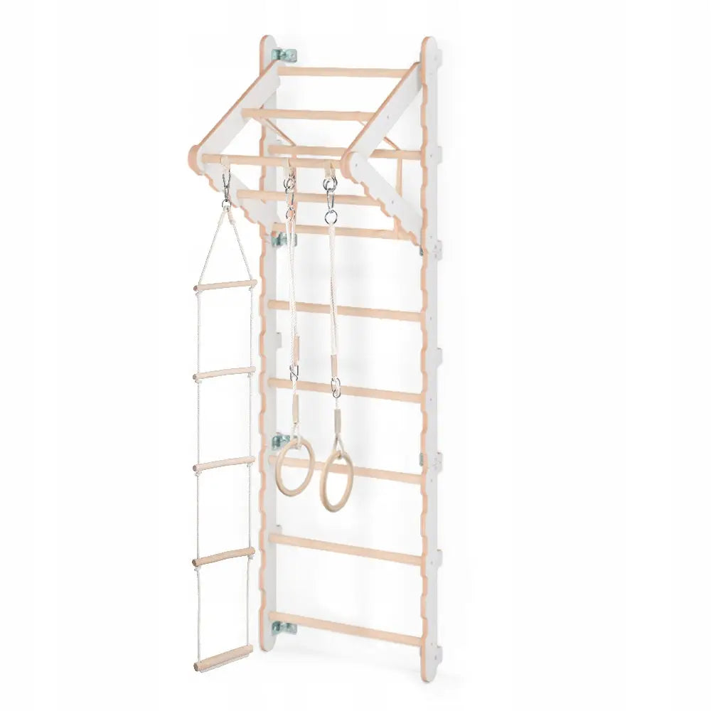 Ribbevegg for barn i lyst tre med hvite detaljer, tau-stige og to treningsringer sett fra skrå vinkel.