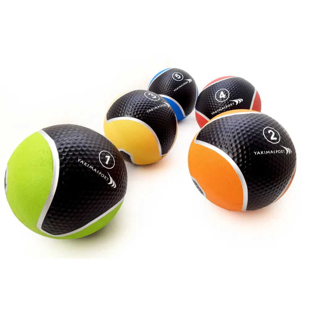 Fem medisinballer i forskjellige farger med sort strukturert overflate, arrangert i skrå vinkel mot hvit bakgrunn.