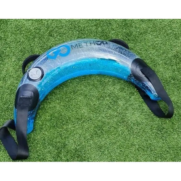 Medisinsk AKUAFIT Bulgarian Bag, gjennomsiktig med blå væske og sorte håndtak, ligger på kunstgress.