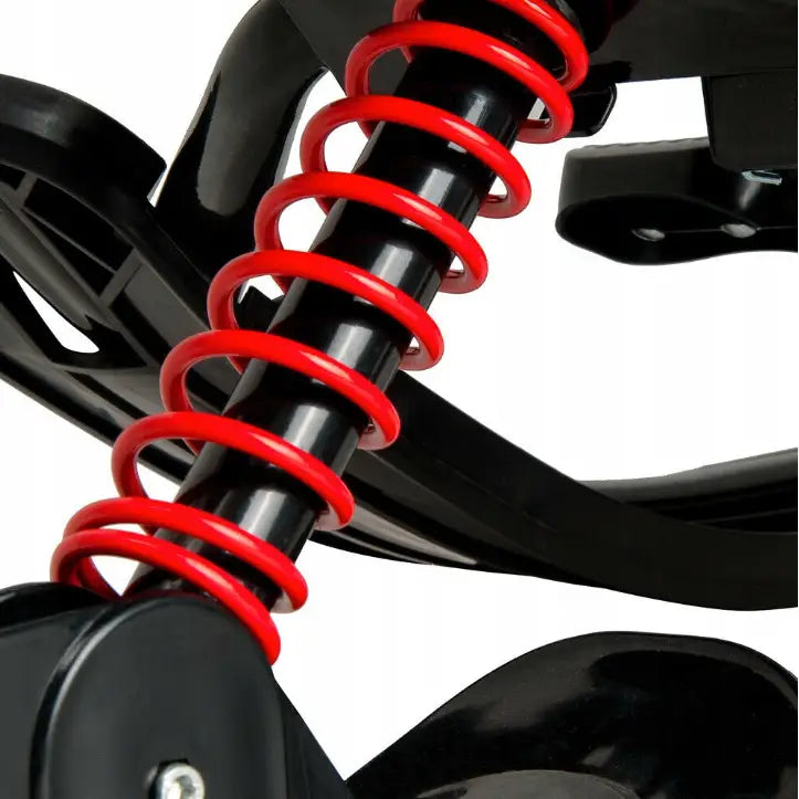 Metall akebrett-skisleder, nærbilde av sort fjær med rød spiral og detaljerte plastkomponenter.