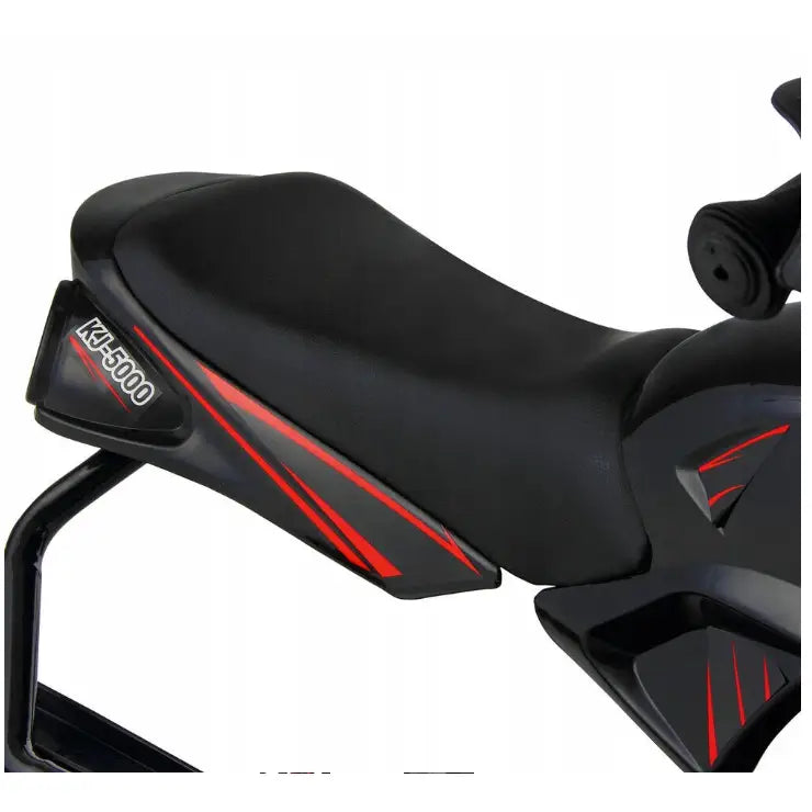 Metall akebrett med sort sete, røde striper og “KJ-5000”-merking, nærbilde av plastdetaljer fra høyre.