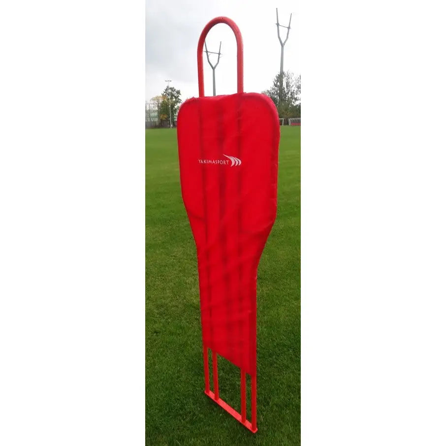 Metall fotballmur, rød treningsfigur i hardplast med håndtak og logo, plassert på grønn gressbane.