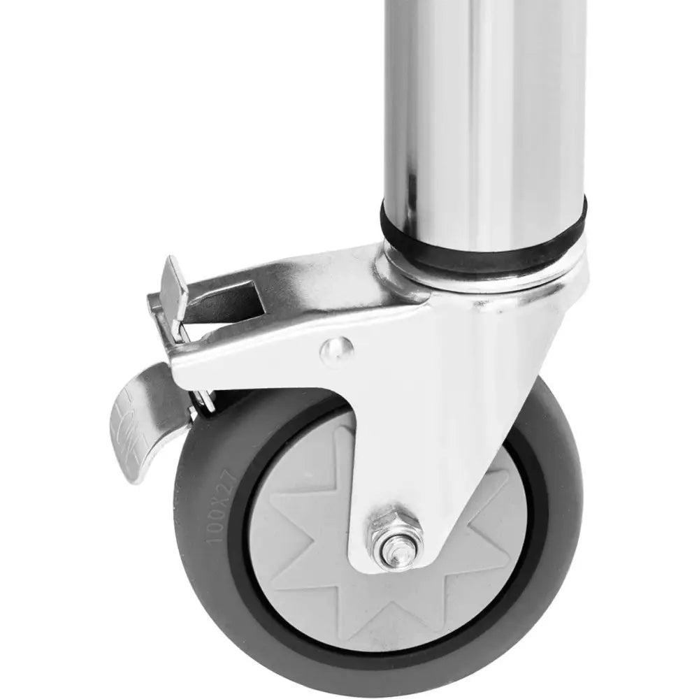 Svingbart grått hjul med brems montert på sølvfarget metallramme til kjøkkenbord, nærbilde fra siden.