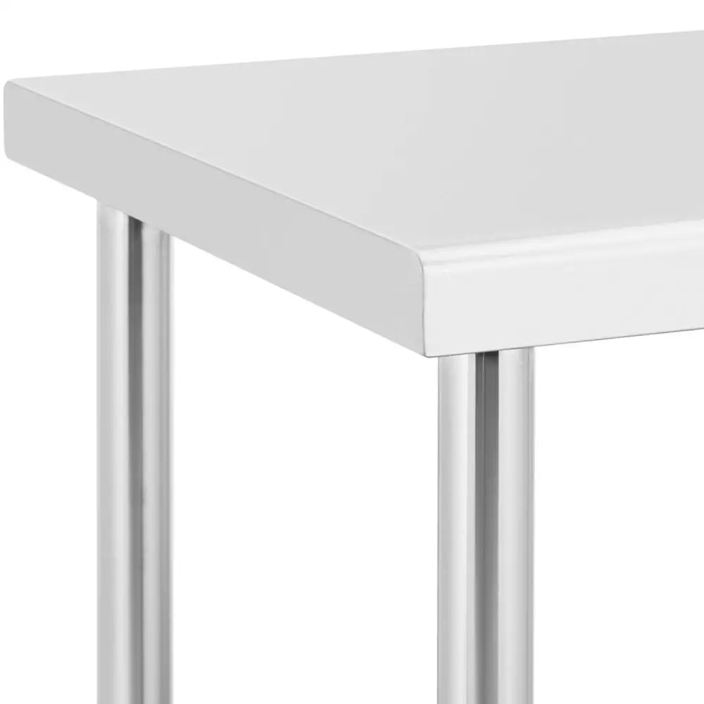 Metallkjøkkenbord på hjul, detalj av hvit bordplatehjørne og blankt, rundt ståleben.