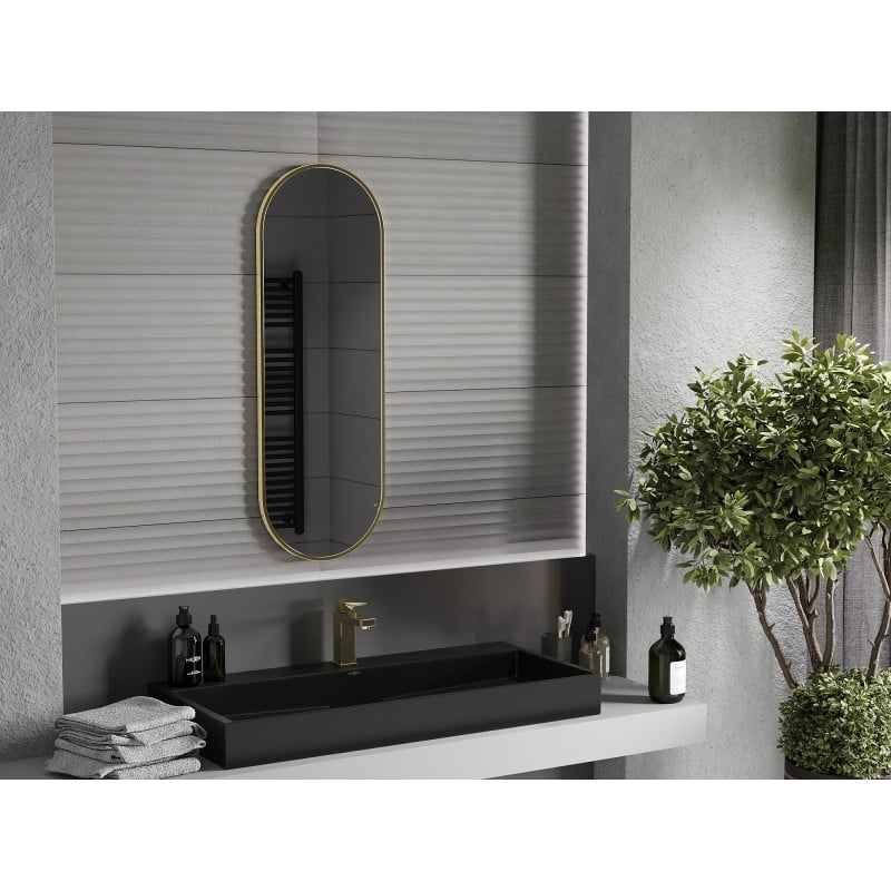Speil til bad ovalt baderomsspeil med gull aluminiumsramme, sort servant og grønne planter.