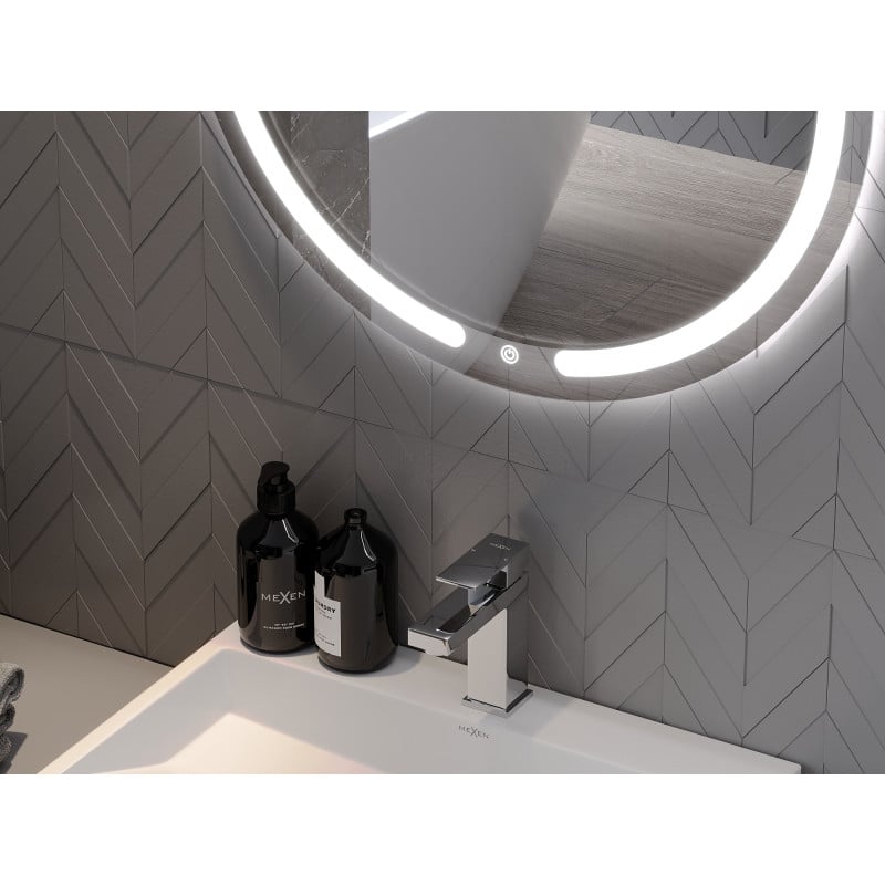 Speil til bad med LED-lys, rundt design, over servantkran og svarte såpedispensere mot grå fliser.