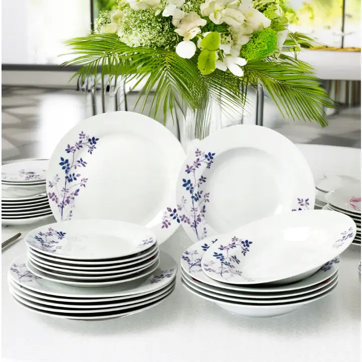 Middagsservise 18 deler, hvitt porselen med lilla og blå blomsterdekor, arrangert på bord med blomsteroppsats.