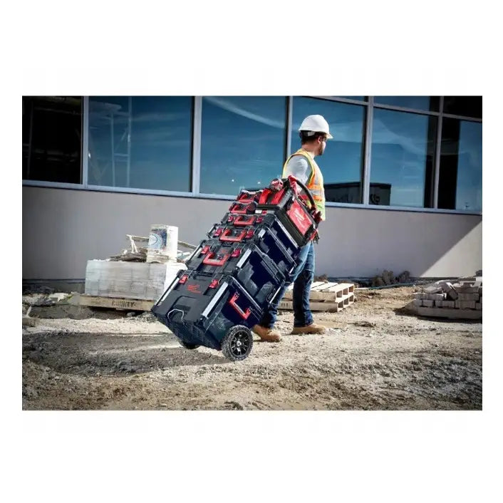 Milwaukee Packout sett, stablede verktøykasser på hjul dras av arbeider over byggeplass.