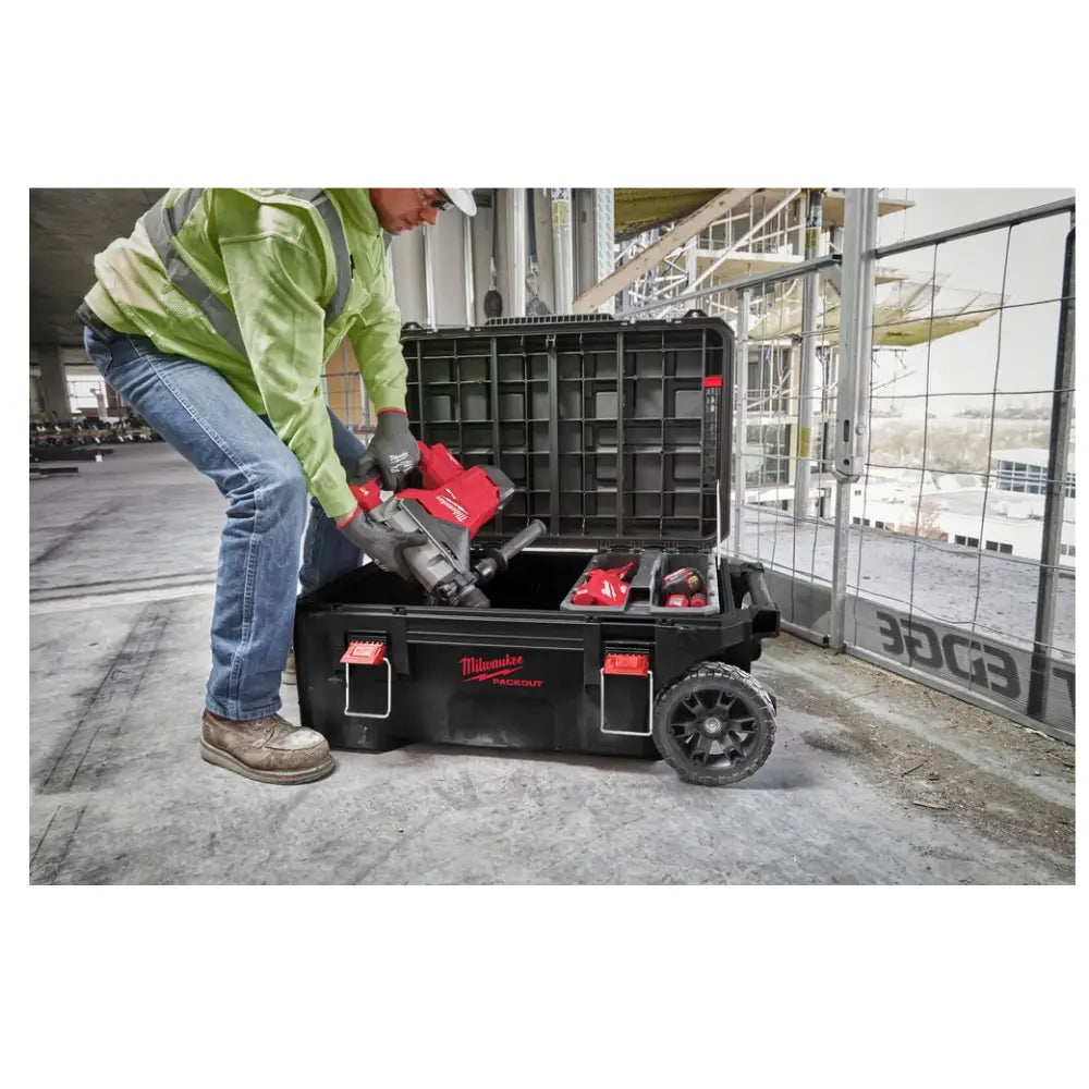 Milwaukee Packout kasse på hjul, åpen på byggeplass mens elektroverktøy plasseres i romslig innside.