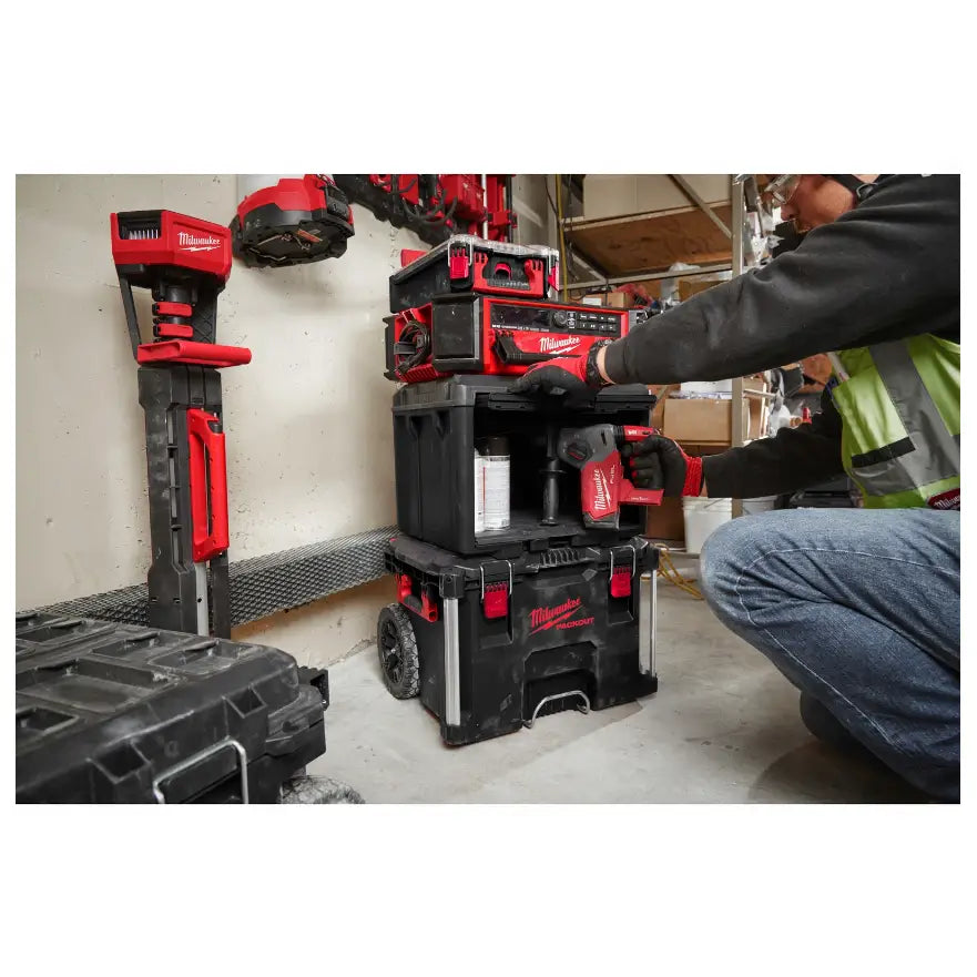 Milwaukee Packout skap, stablede svarte og røde verktøykasser fra siden, person legger inn elektroverktøy.