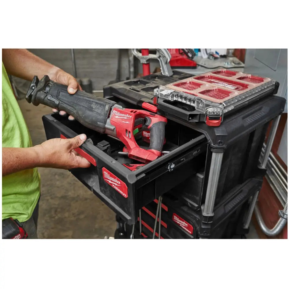 Milwaukee Packout verktøykasse med elektrisk bajonettsag i rød og svart skuff, sett fra siden mens den åpnes.