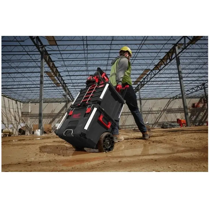 Milwaukee Packout verktøykasse med 4 skuffer trilles på gjørmete byggeplass av person i arbeidsklær.