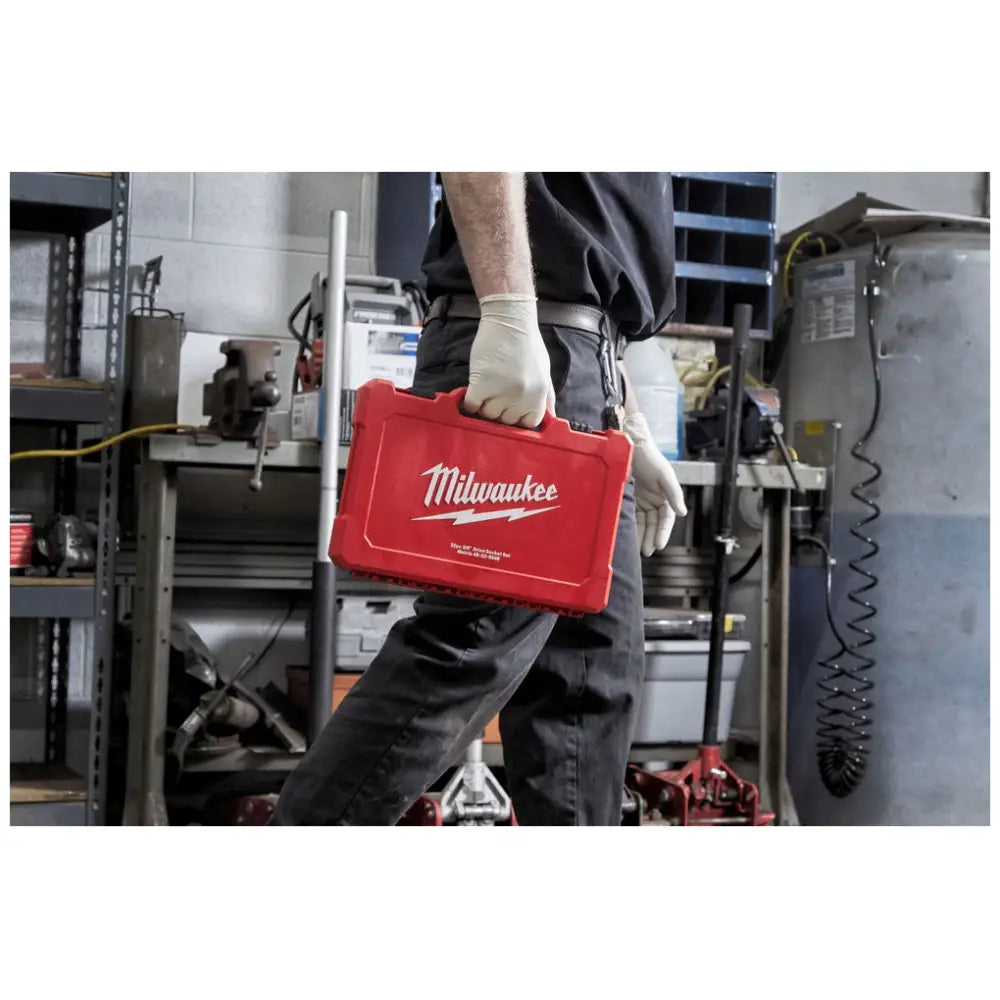 Milwaukee sett med hylsenøkler i rød koffert bæres med hansker i verksted, sideperspektiv.