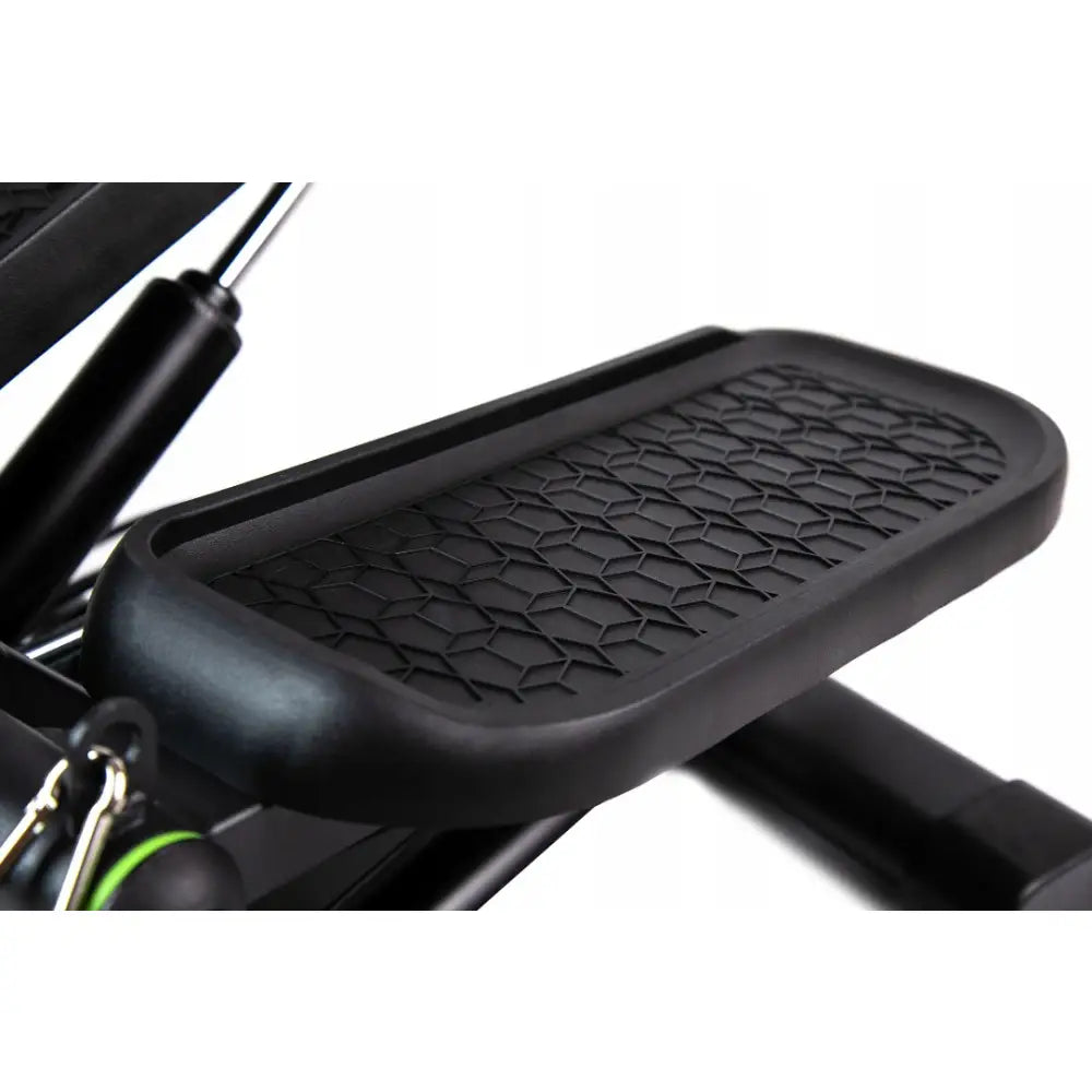 Mini stepper med motstandsbånd, nærbilde av strukturert sort pedal med geometrisk mønster og synlige fjærdetaljer.